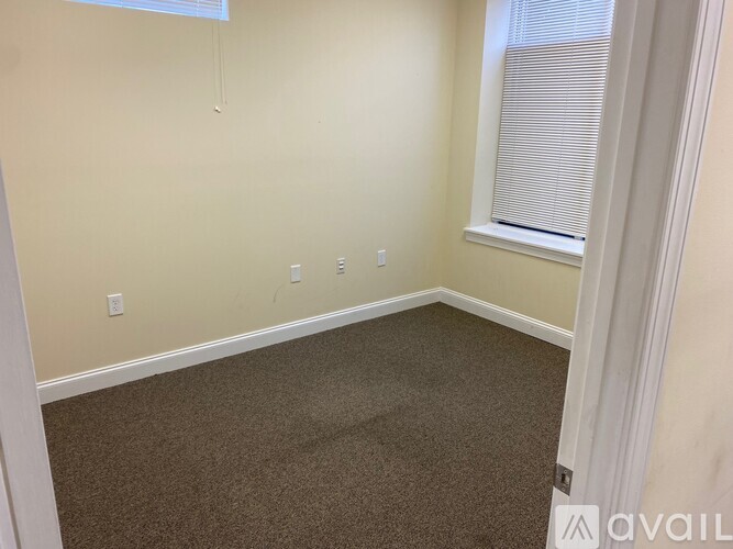 A room with a carpeted floor and a window with blinds.