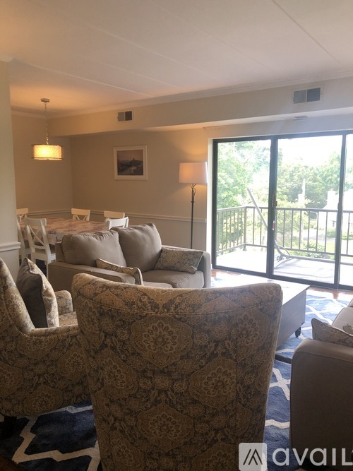 A living room with a patterned chair in the foreground and a painting on the wall.