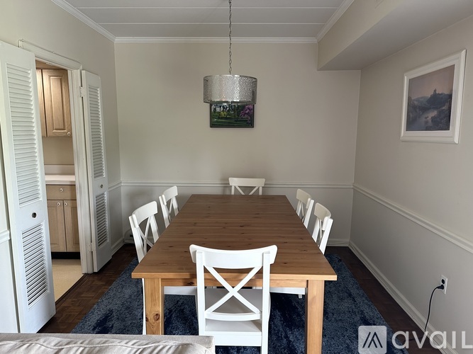 A dining room with a wooden table and white chairs.