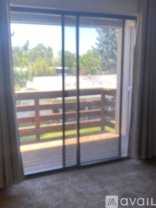 A balcony with a railing and a view of trees and a house.