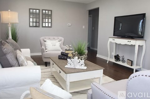 A living room with a white couch, a coffee table with a plant and a camera on it, and a television on a stand.