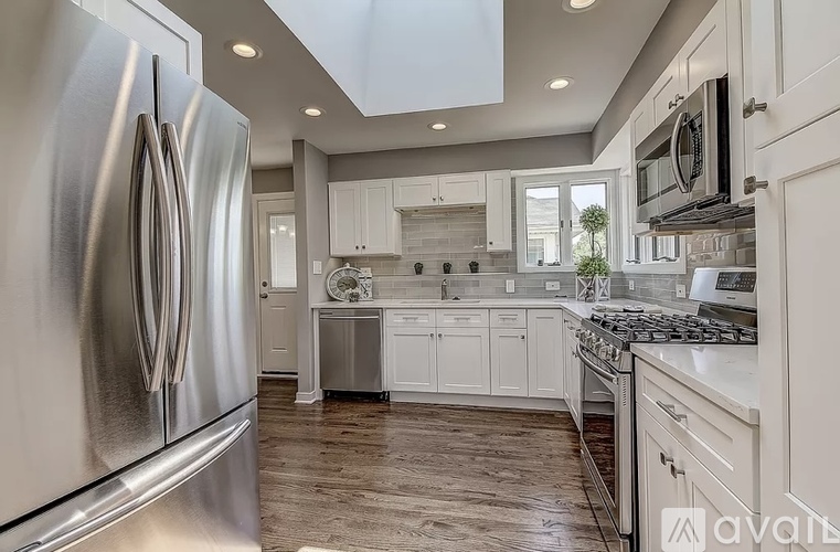 A modern kitchen with a stainless steel refrigerator and white cabinets.