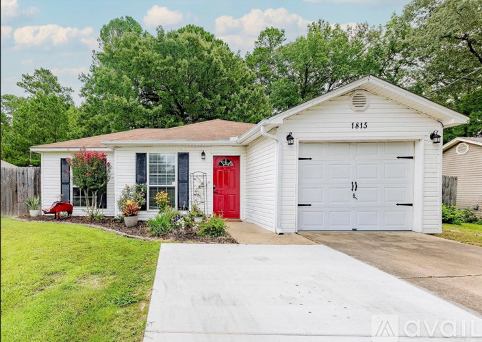 A white house with a red door and a garage door.
