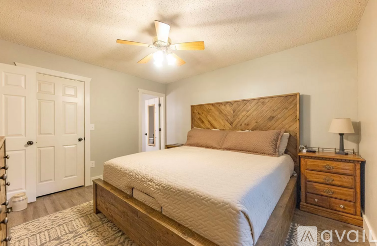 A bedroom with a bed, dresser, and ceiling fan.