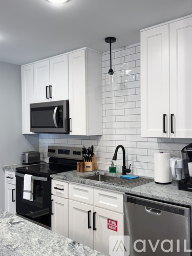A kitchen with white cabinets and a black microwave.