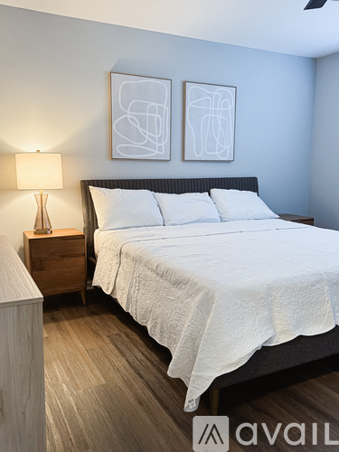A bedroom with a bed, nightstand, and two framed artworks on the wall.