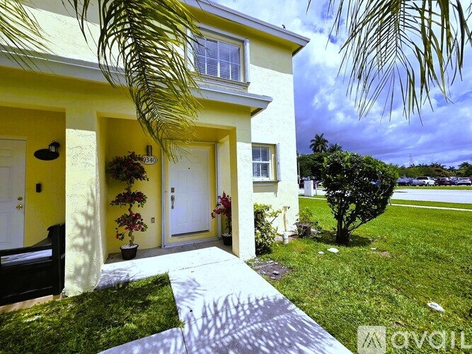 A modern house with a front yard and palm trees.
