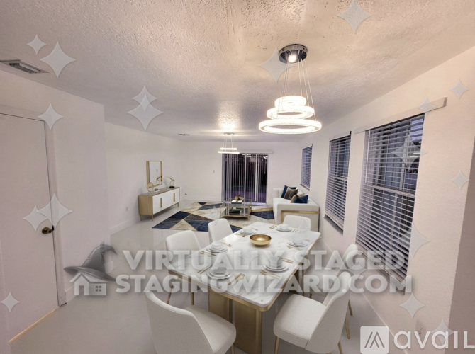 A spacious room with white walls and floor, a ceiling light, and a window with blinds.