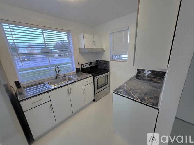 A kitchen with white cabinets and a black countertop.
