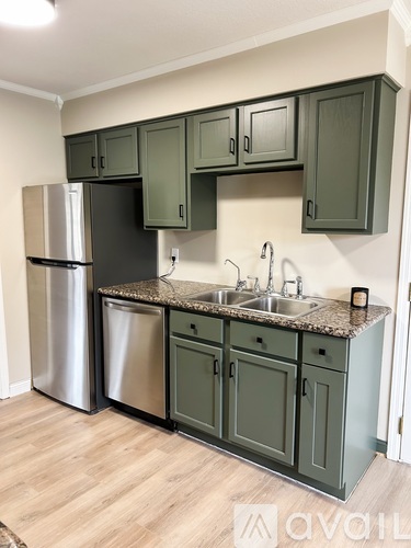A kitchen with green cabinets and a stainless steel refrigerator.