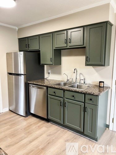 A kitchen with green cabinets and a stainless steel refrigerator.