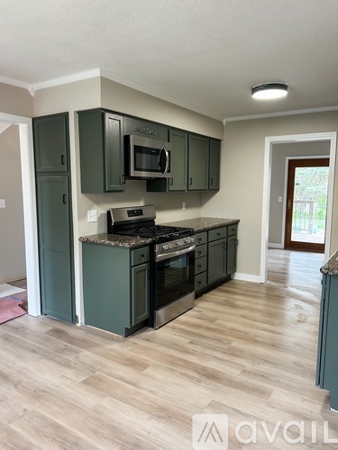 A kitchen with dark green cabinets and a granite countertop.