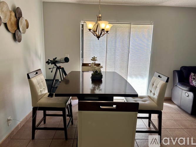 A dining room with a table, chairs, and a telescope on a tripod.