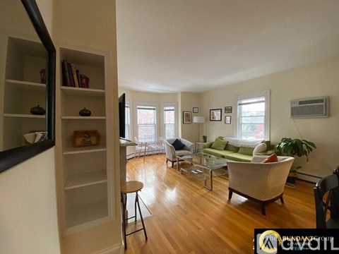 A living room with a green couch and a wooden floor.