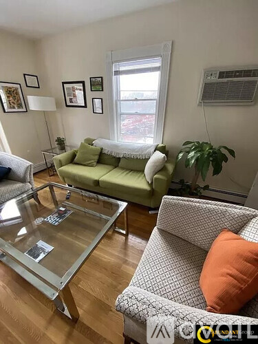 A living room with a green couch, a glass coffee table, and a grey armchair.