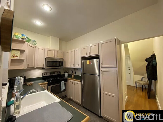 A kitchen with white cabinets and a stainless steel refrigerator.