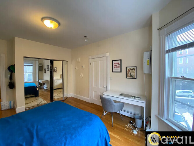A bedroom with a blue bed and a desk with a chair.