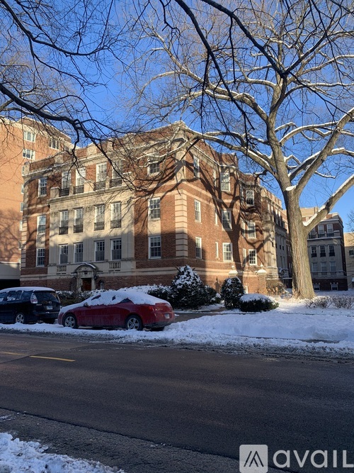 A car covered in snow is parked in front of a large building.