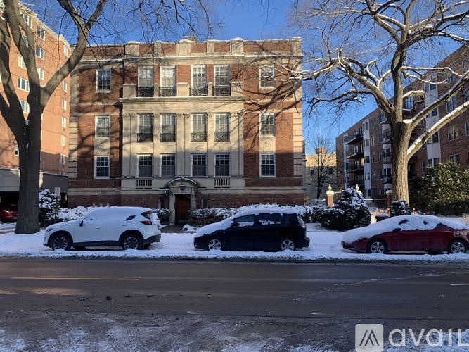 A white car is parked in front of a building with a tree in the background.