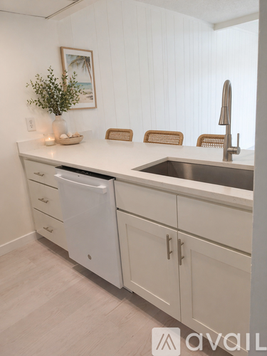 A kitchen with white cabinets and a white dishwasher.