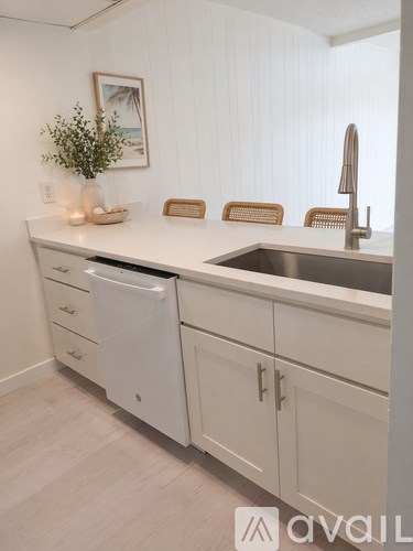 A kitchen with white cabinets and a white dishwasher.