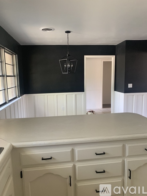 A kitchen with black walls and white cabinets.