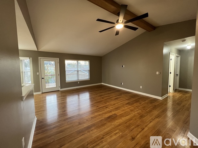 A spacious room with wooden floors and a ceiling fan.