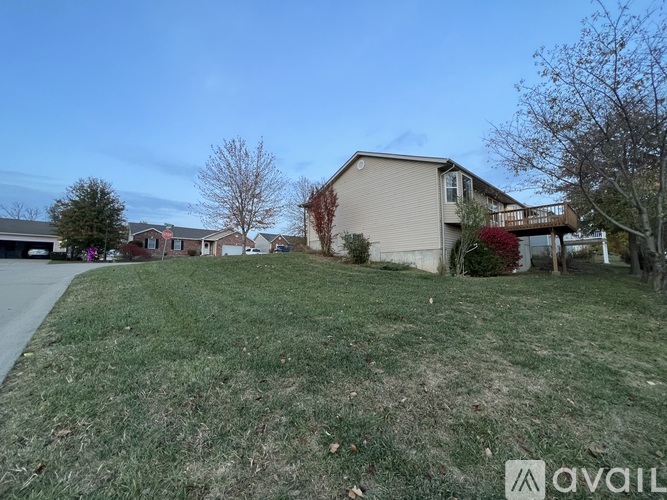 A grassy area with a house and trees in the background.