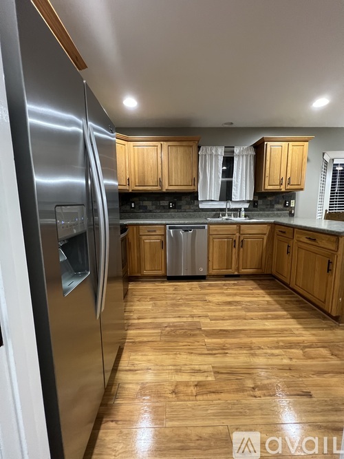A kitchen with wooden cabinets and a stainless steel refrigerator.