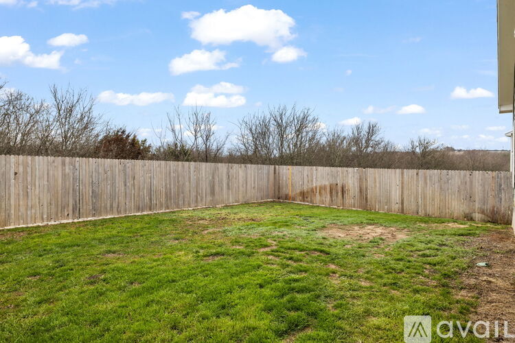 A backyard with a wooden fence and a grassy area.