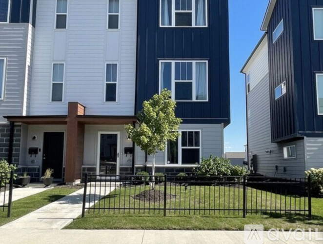 A modern two-story apartment building with a black fence in front.