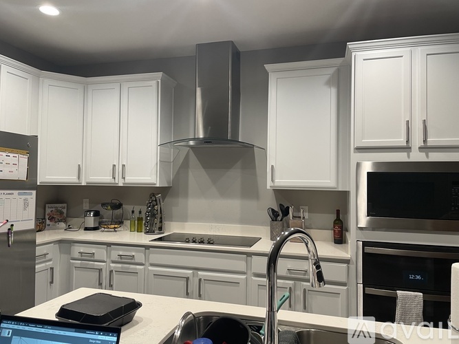 A modern kitchen with white cabinets and stainless steel appliances.