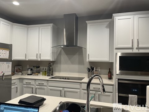 A modern kitchen with white cabinets and stainless steel appliances.