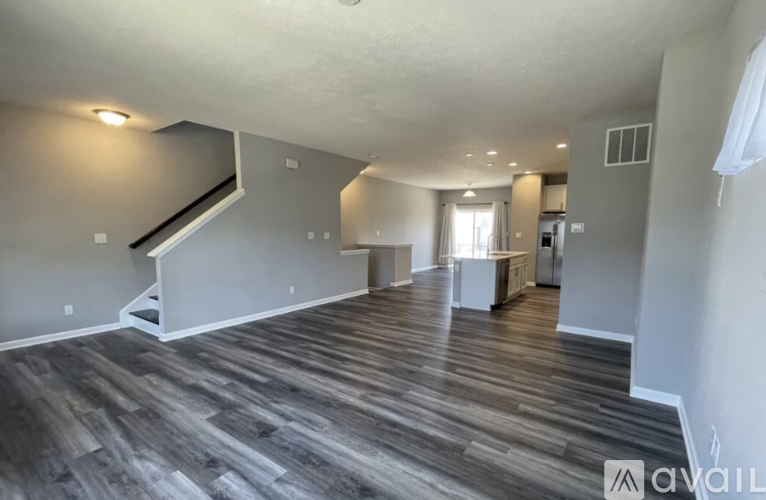 A spacious living room with wood flooring and a staircase leading to the upper level.