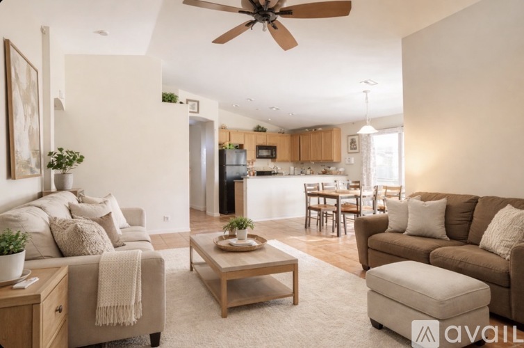 A living room with a brown couch, a coffee table, and a ceiling fan.