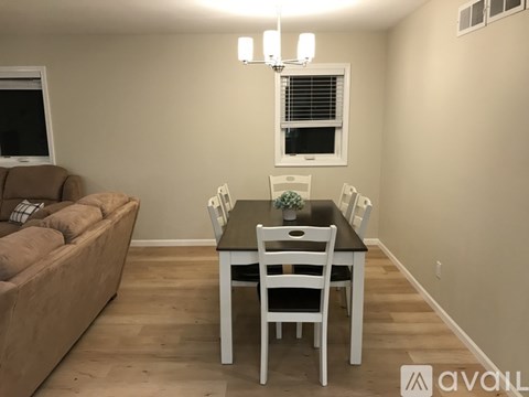 A dining room with a brown couch and a white table.