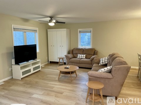 A living room with a brown couch, a white cabinet, and a flat screen TV.