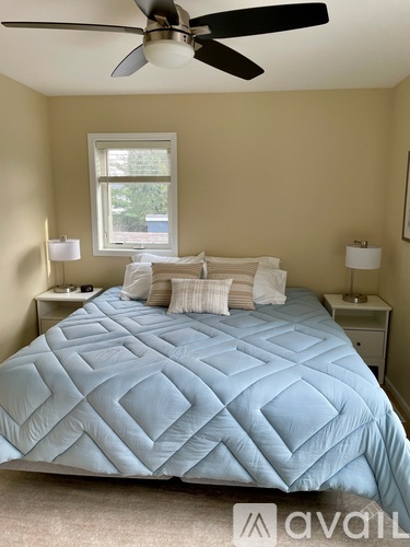 A bedroom with a blue bedspread and two white bedside tables.