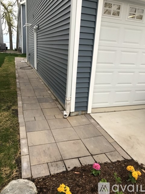A walkway leads to a white garage door.