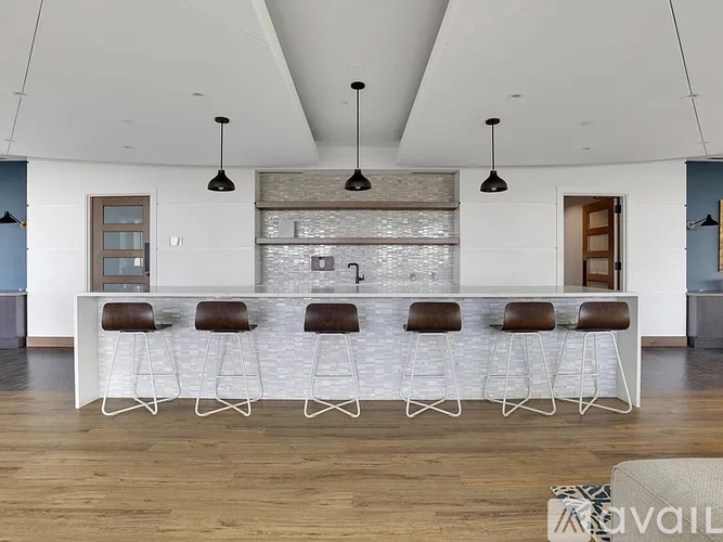 A modern kitchen with a white island and bar stools.