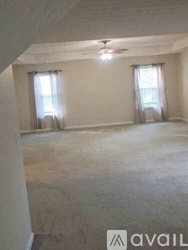 A room with a fan and two windows.