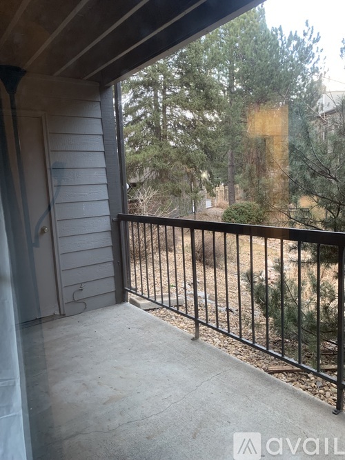 A balcony with a black railing and a view of trees.