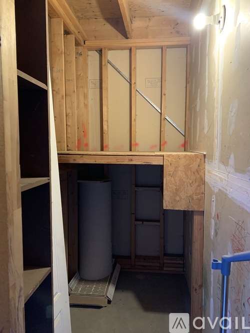 A room under construction with wooden framing and a blue step stool.