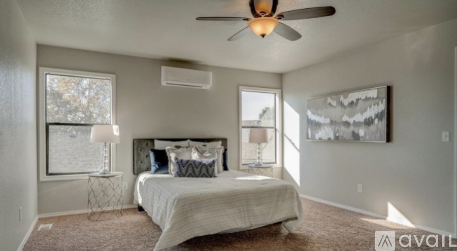 A bedroom with a bed, a ceiling fan, and a window.