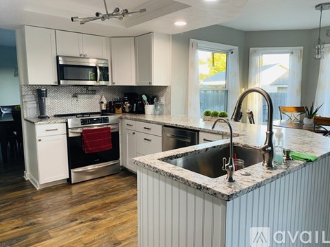 A kitchen with a sink, stove, and microwave.