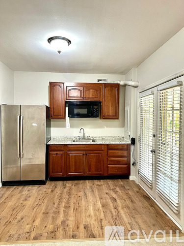 A kitchen with wooden cabinets and a stainless steel refrigerator.