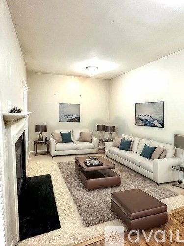 A living room with a white couch, a fireplace, and a painting on the wall.