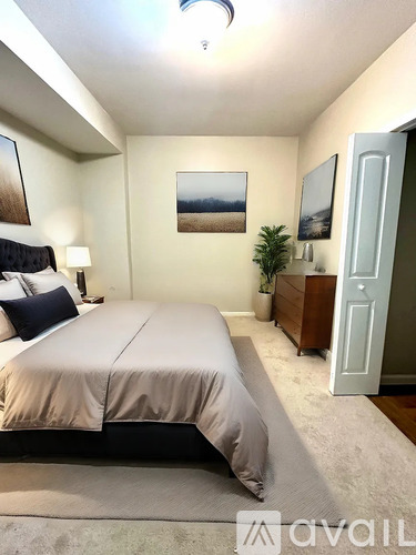 A bedroom with a bed, nightstand, and a painting on the wall.