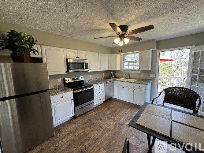 A kitchen with a refrigerator, microwave, oven, and a dining table.