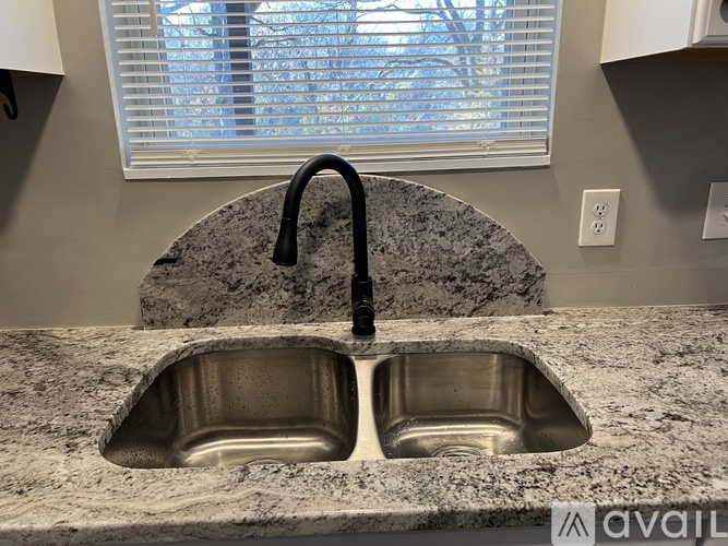 A kitchen sink with a black faucet and a granite countertop.